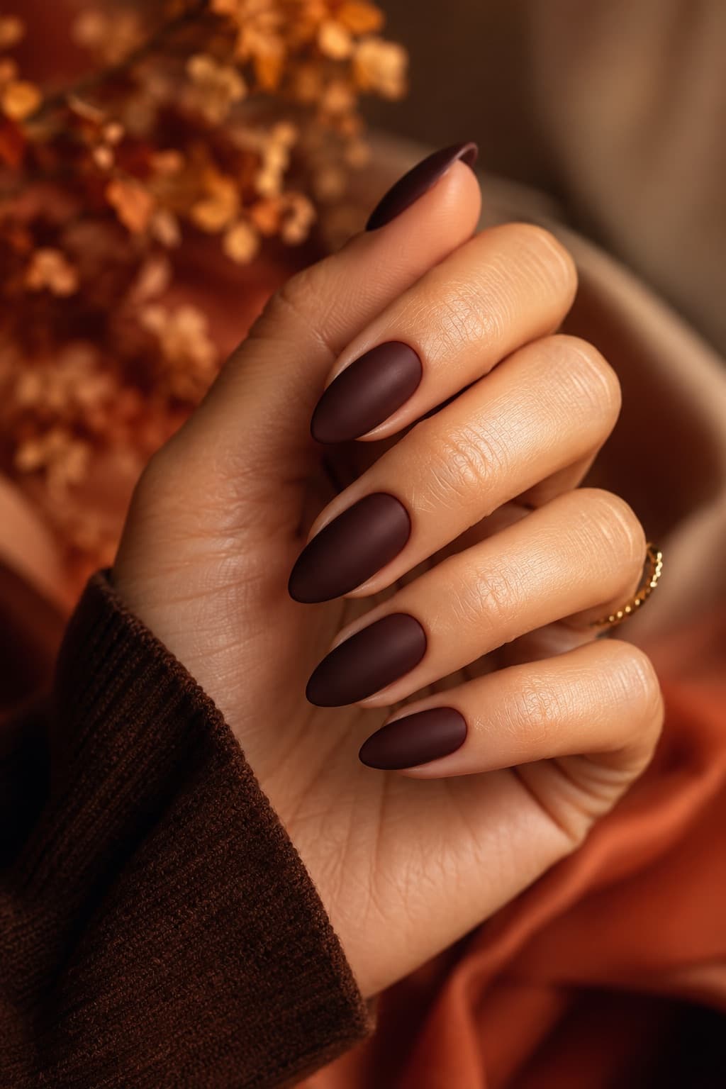 Matte espresso brown almond nails in warm autumn light