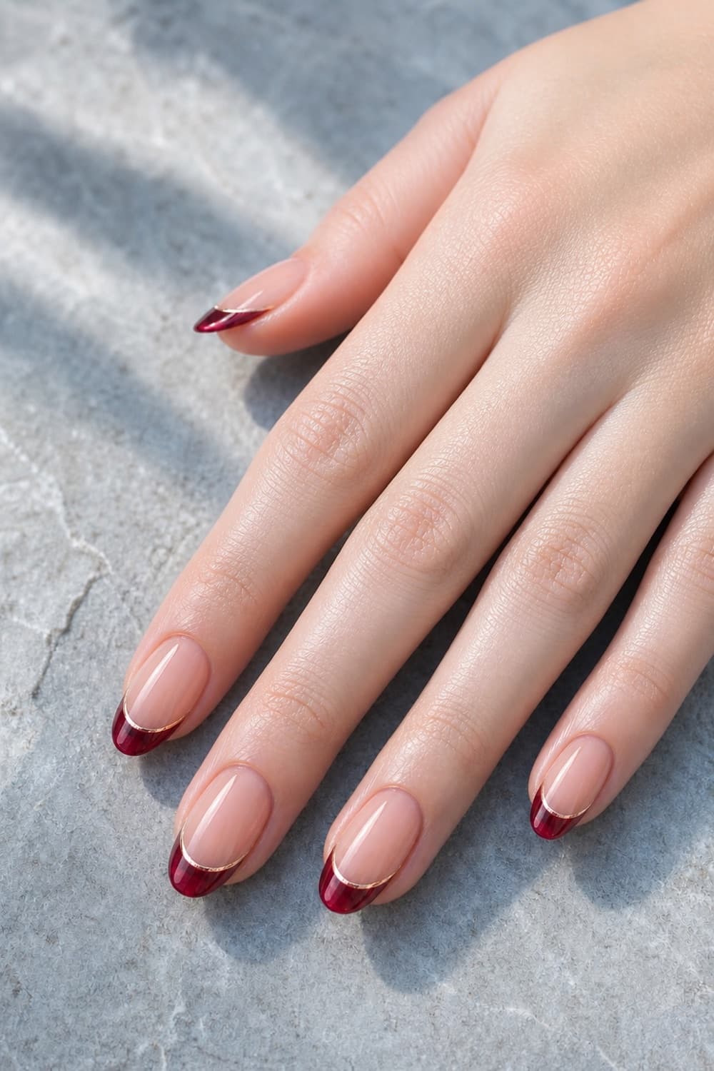 Medium oval Christmas nails with ruby glass French tips and a fine champagne chrome outline.
