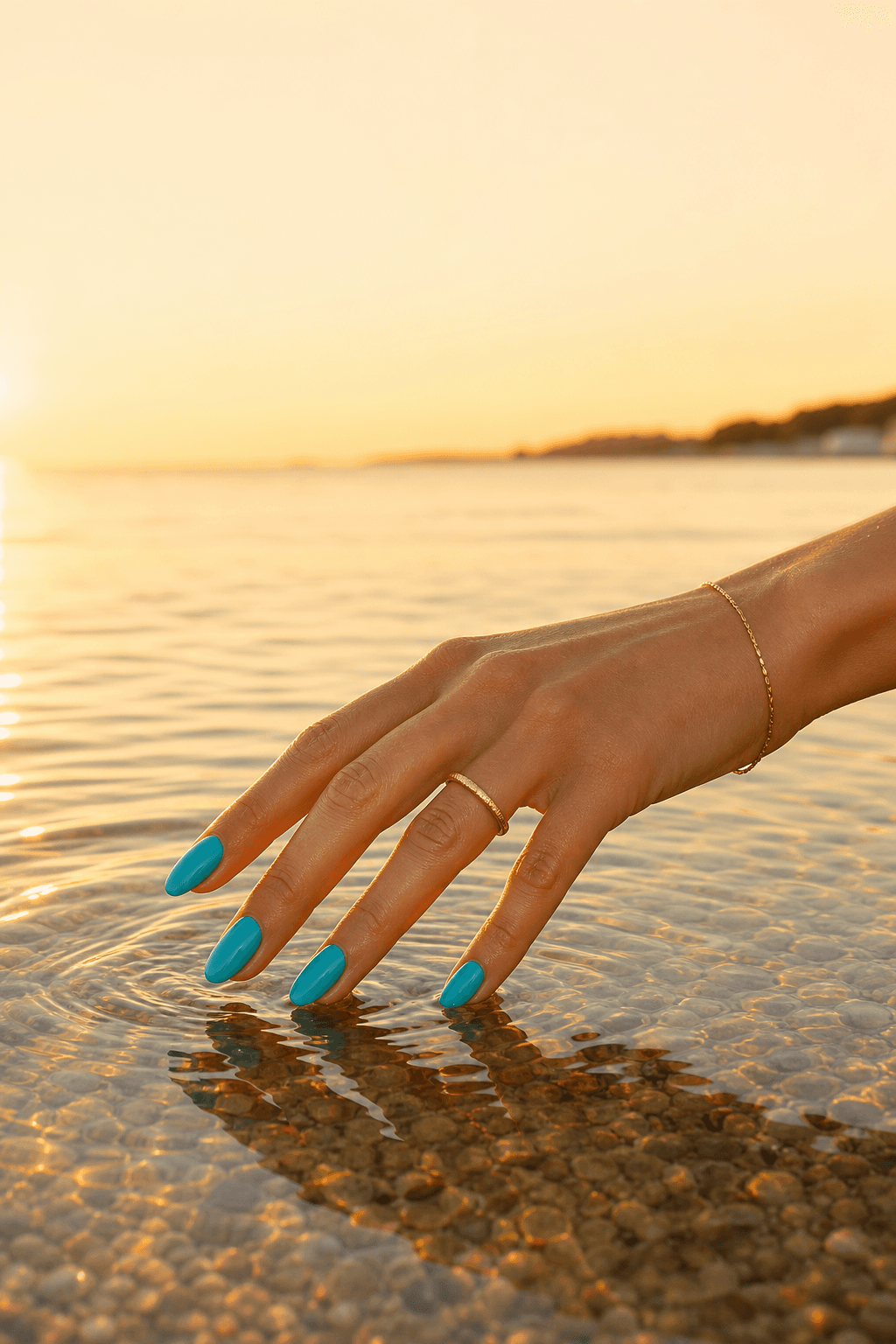 Turquoise almond nails photographed above clear seawater at sunset